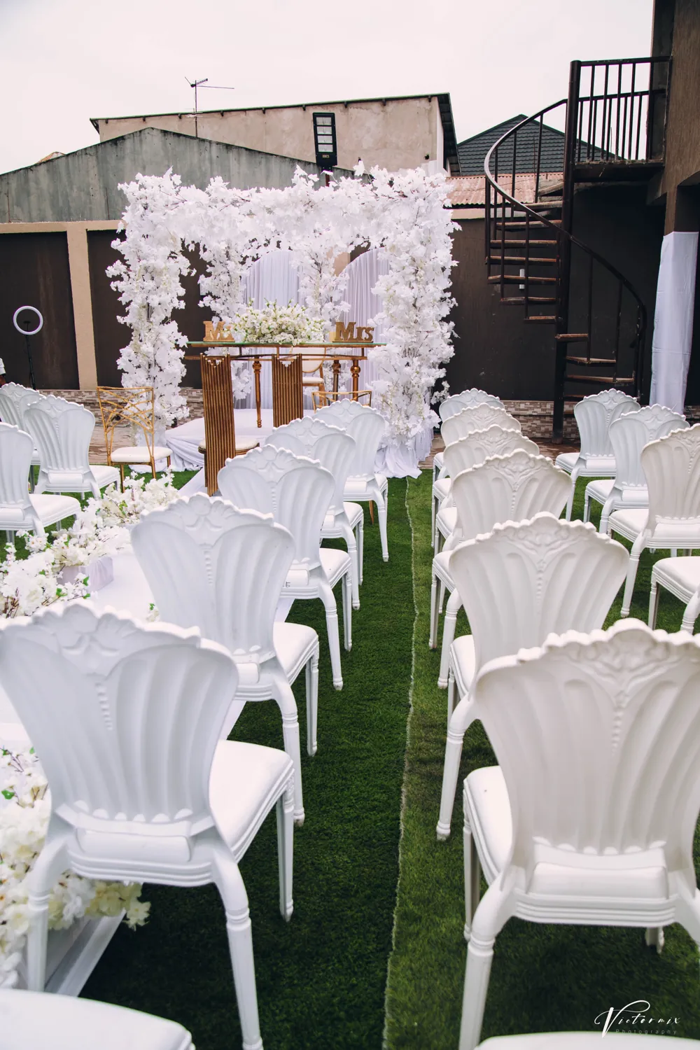 Rows of white chairs on a lawn, waiting for a garden ceremony.